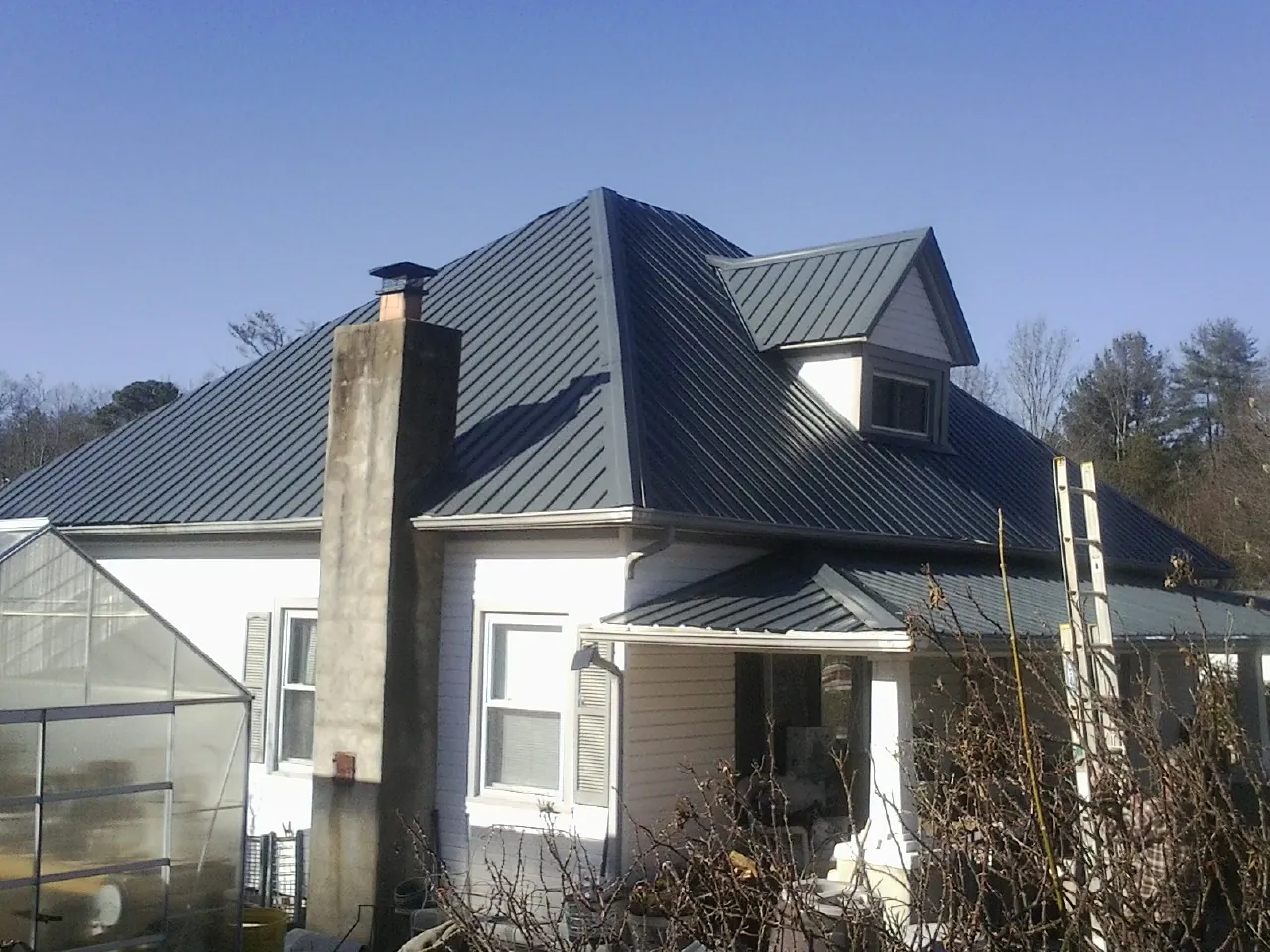 Dark blue standing seam metal roof on a white farmhouse with dormer — Slate & Tile Roof Repair by Roofing Brothers in Dana Point