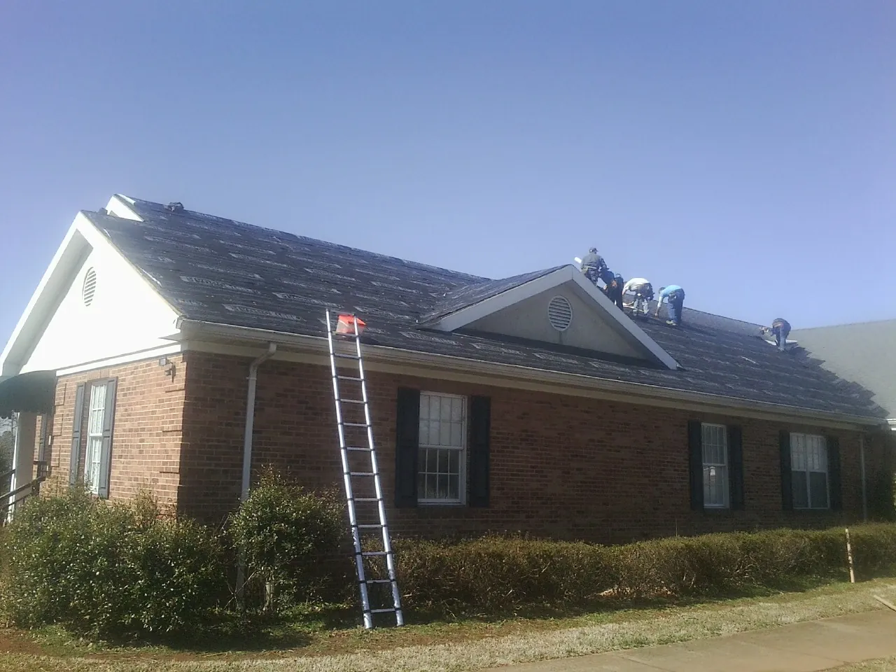 Crew tearing shingles off a brick ranch roof with a ladder set — Metal Roof Repair work by our crew in Dana Point