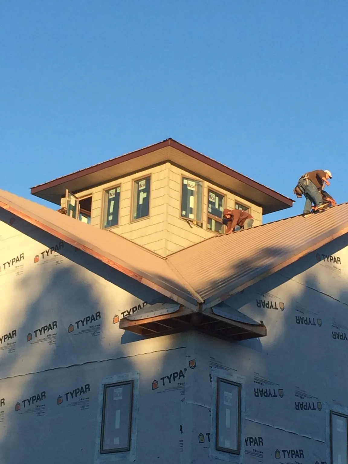 Roofers working around a rooftop cupola on a new metal roof at sunset — Roof Waterproofing in Dana Point by Roofing Brothers